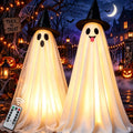 Two glowing white hanging ghosts in black witch hats in a spooky yard at night