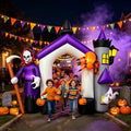 Inflatable haunted castle gateway arch with purple turrets and a reaper, children walking through at dusk