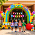 Inflatable rainbow crayon archway with a Happy Holiday banner, a yellow school bus and an apple, with children underneath