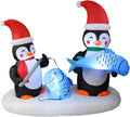 Inflatable scene of two penguins in Santa hats ice fishing, one holding a blue fish