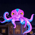 Purple inflatable octopus with a grinning face draped over a house roof at night