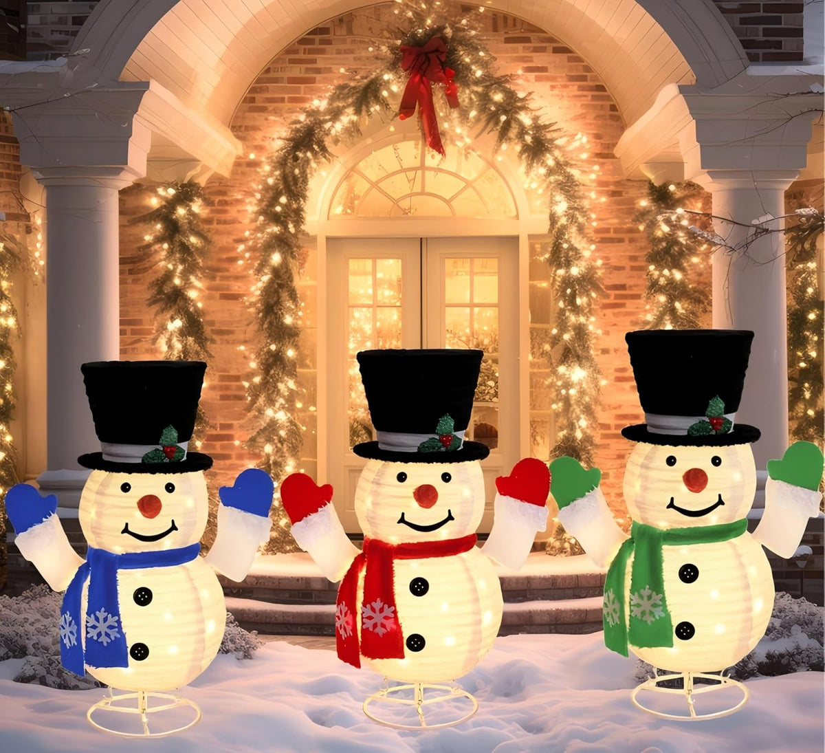 Three pop-up lighted snowmen in top hats and scarves standing in front of a garlanded doorway