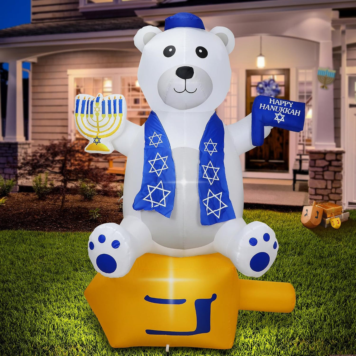 Inflatable white bear in a blue scarf holding a Star of David beside a menorah on a front lawn