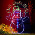 LED outline of a snowman juggling snowballs glowing on a lawn at night