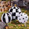 Three inflatable pumpkins in black and white stripes, checks and polka dots in a Halloween yard
