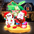 Inflatable tropical Christmas scene with Santa in sunglasses and a snowman under a palm tree on a sand base