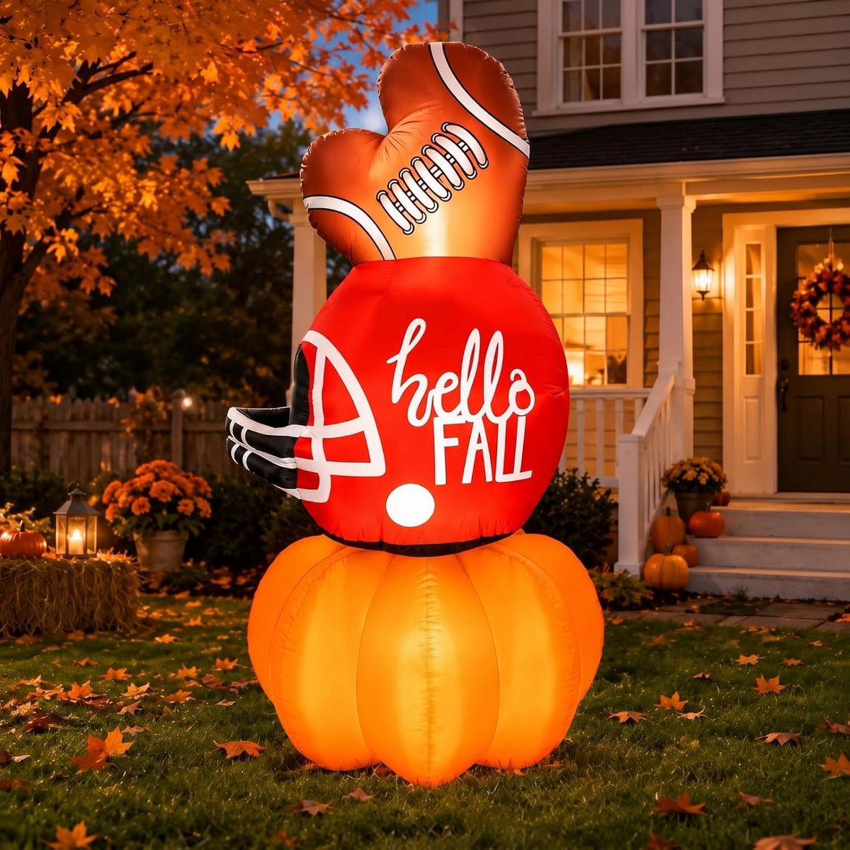 Inflatable football on top of orange pumpkins with a Hello Fall sign on a porch with fall decor