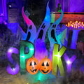 Inflatable SPOOKY letters with pumpkin faces and tall purple-lit ghosts behind them at night