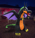 Inflatable black dragon with orange markings and purple wings on a lawn at night